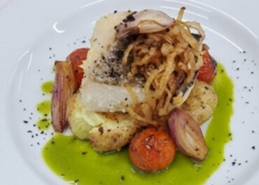 Confit cod with parsley vinaigrette on a bed of potatoes with cherry tomatoes and shallots.