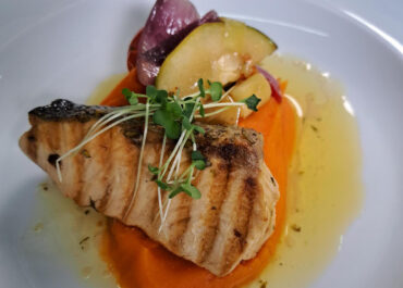 Grilled Greater Amberjack with herb sauce on a bed of mashed sweet potatoes and sautéed vegetables